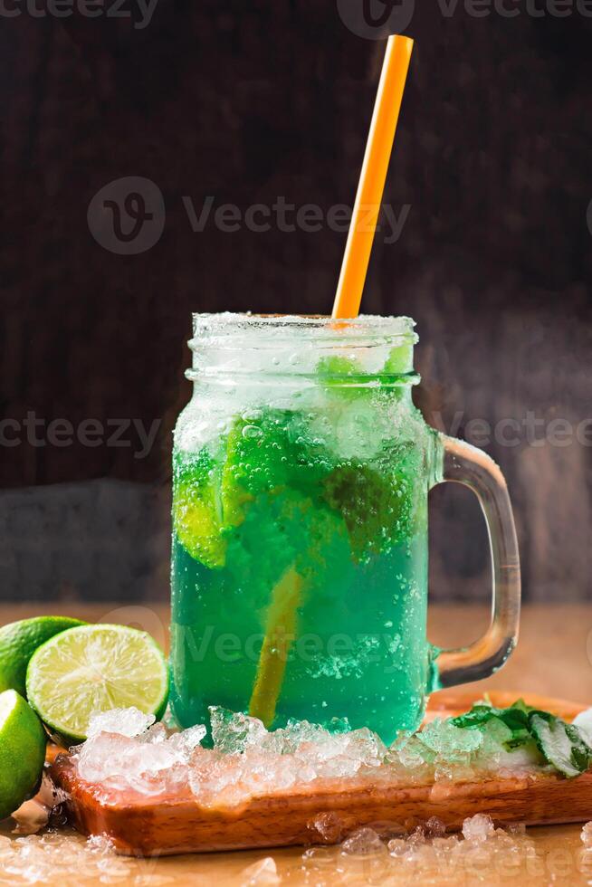 MOCKTAIL MOJITO with Refreshing Mint Lemonade with Lime and Ice served in jar with straw isolated on wooden board side view of perfect drink for a hot summer day photo