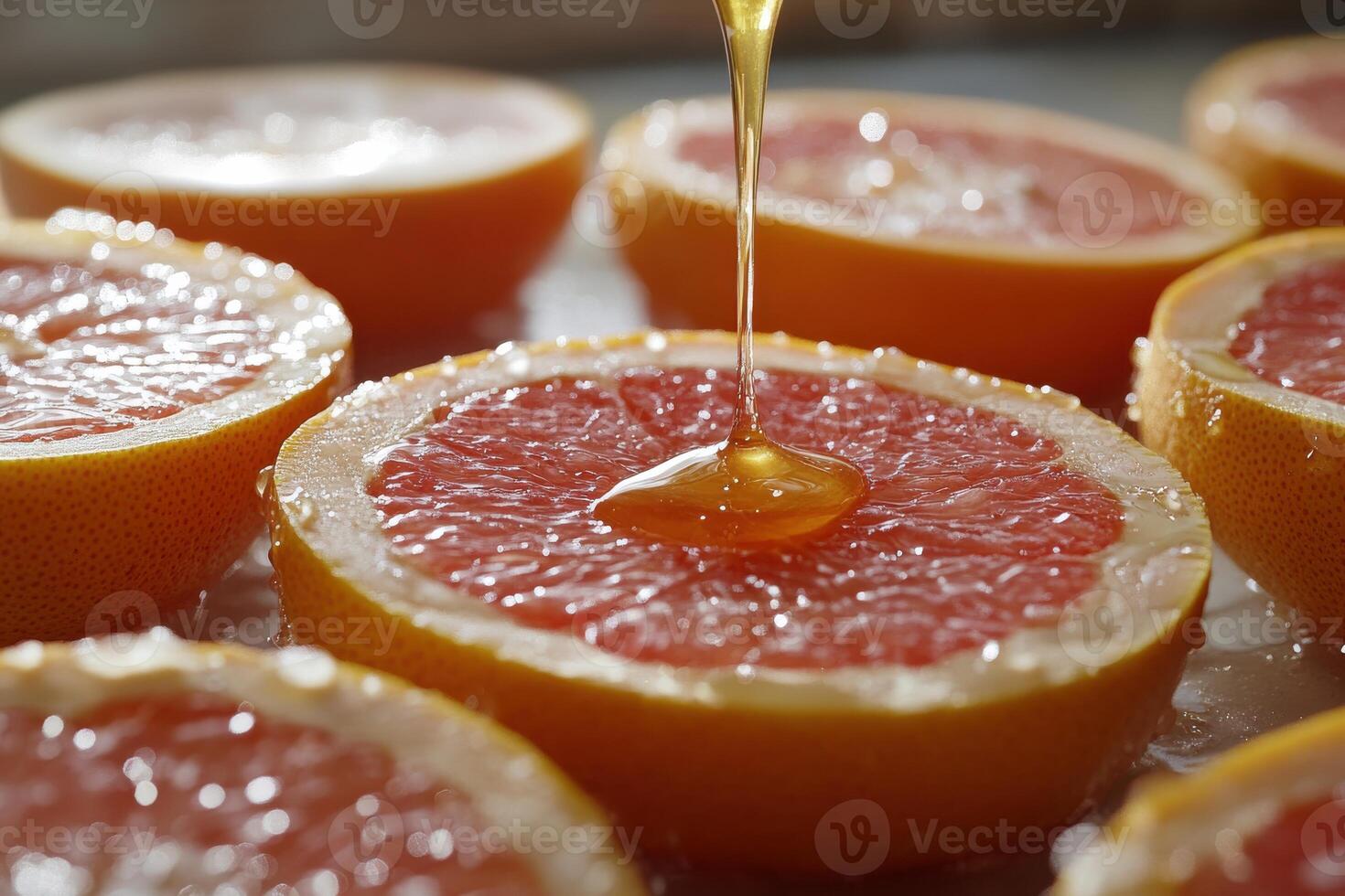 Drizzling honey onto fresh grapefruit halves on a bright kitchen counter during daylight photo