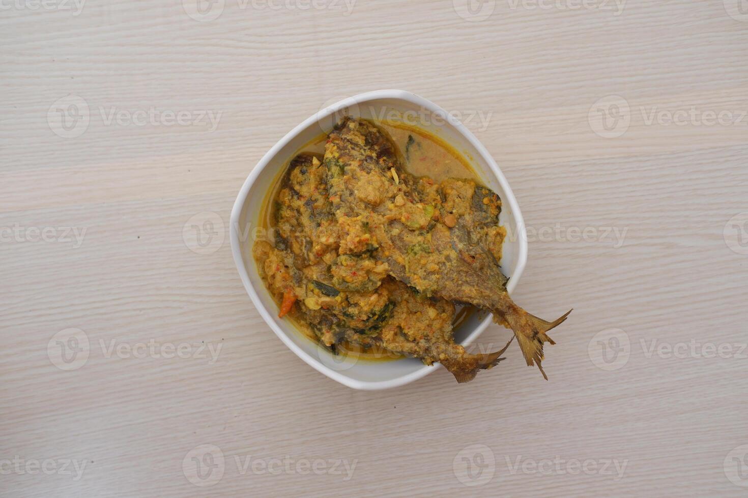 Fried fish with curry in a bowl on a wooden table. photo