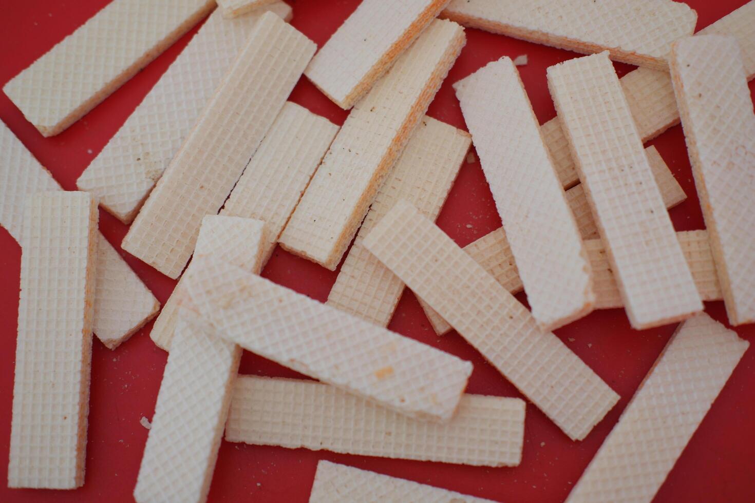 beige wafer cookies with a cream filling is scattered on a bright red surface photo