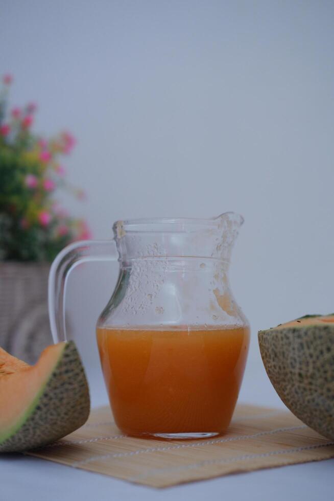 Melon juice in a glass and fresh melon on the table photo