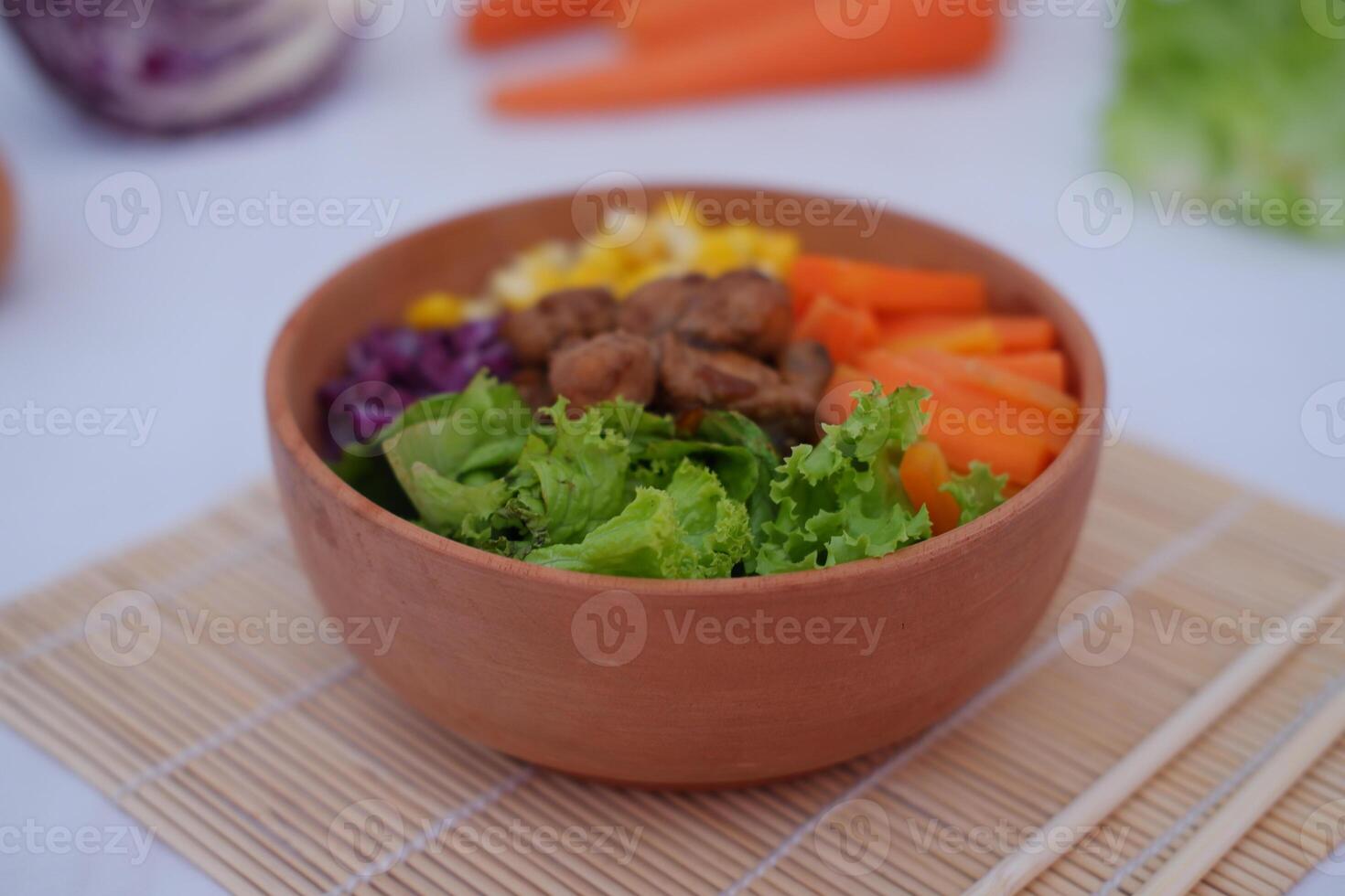 Salad with carrot, corn and lettuce in a clay bowl. photo