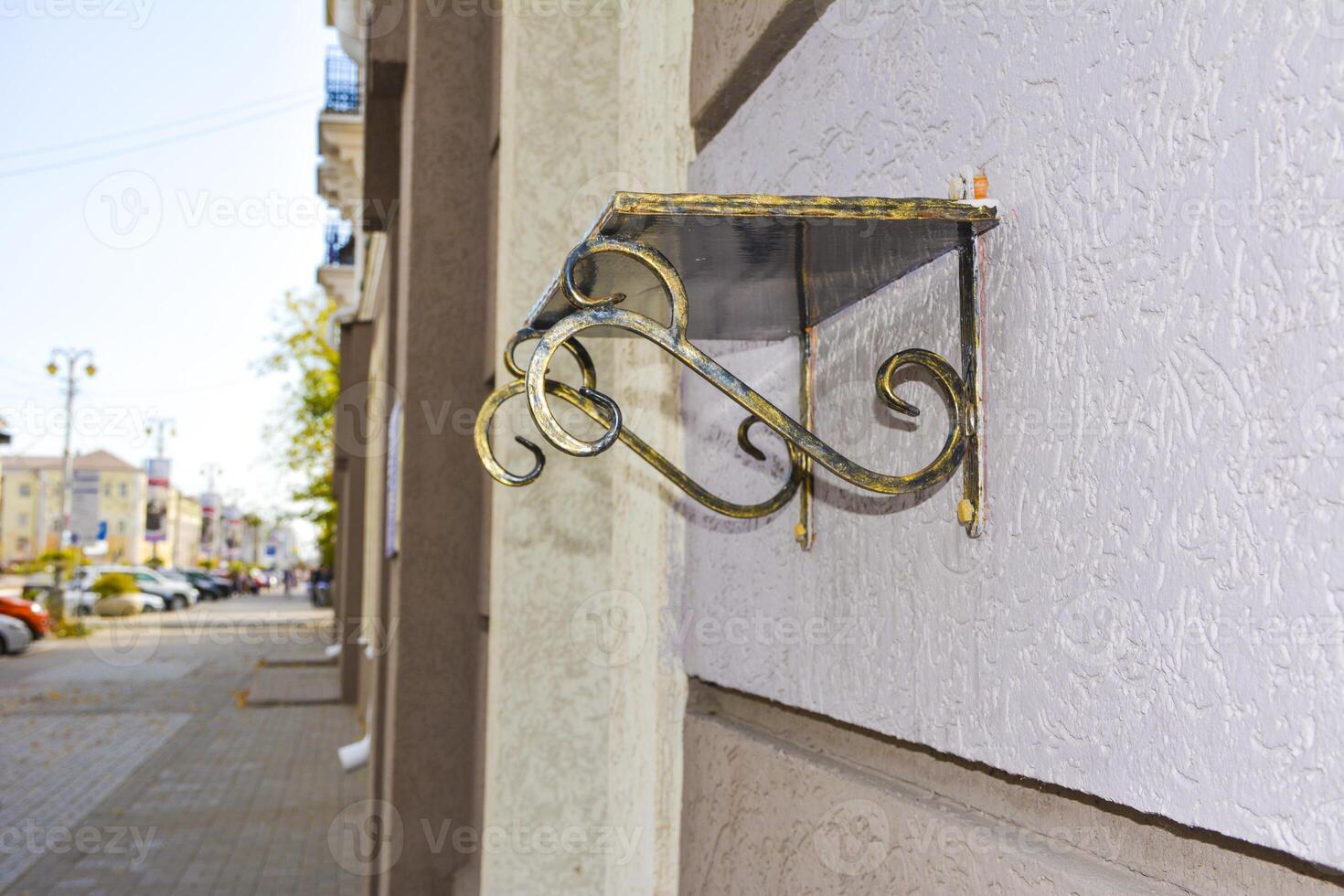 Forged Brackets with a memorial shelve for flowers. Bronze forged shelf with beautiful holders with scrolls and ornaments on the facade of a building. photo