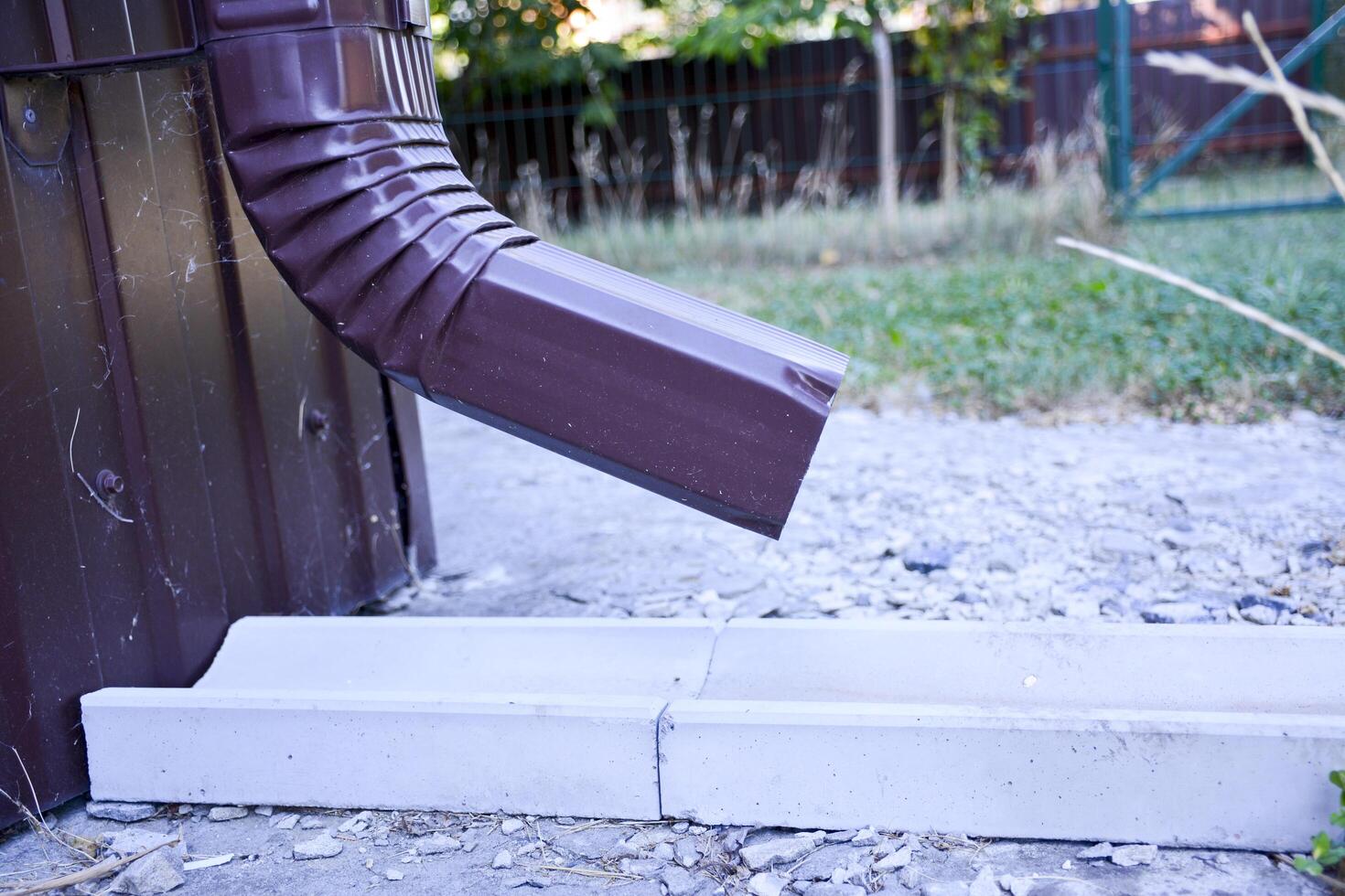 A close-up of a brown gutter pipe. The installation that drains water from the roof. Drainage system attached to the house. Guttering system. photo