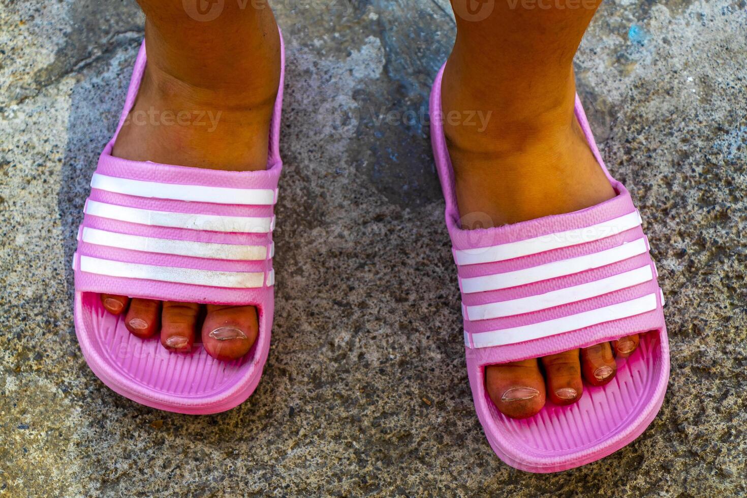 Dirty girls feet in pink slippers in Alajuela Costa Rica. photo