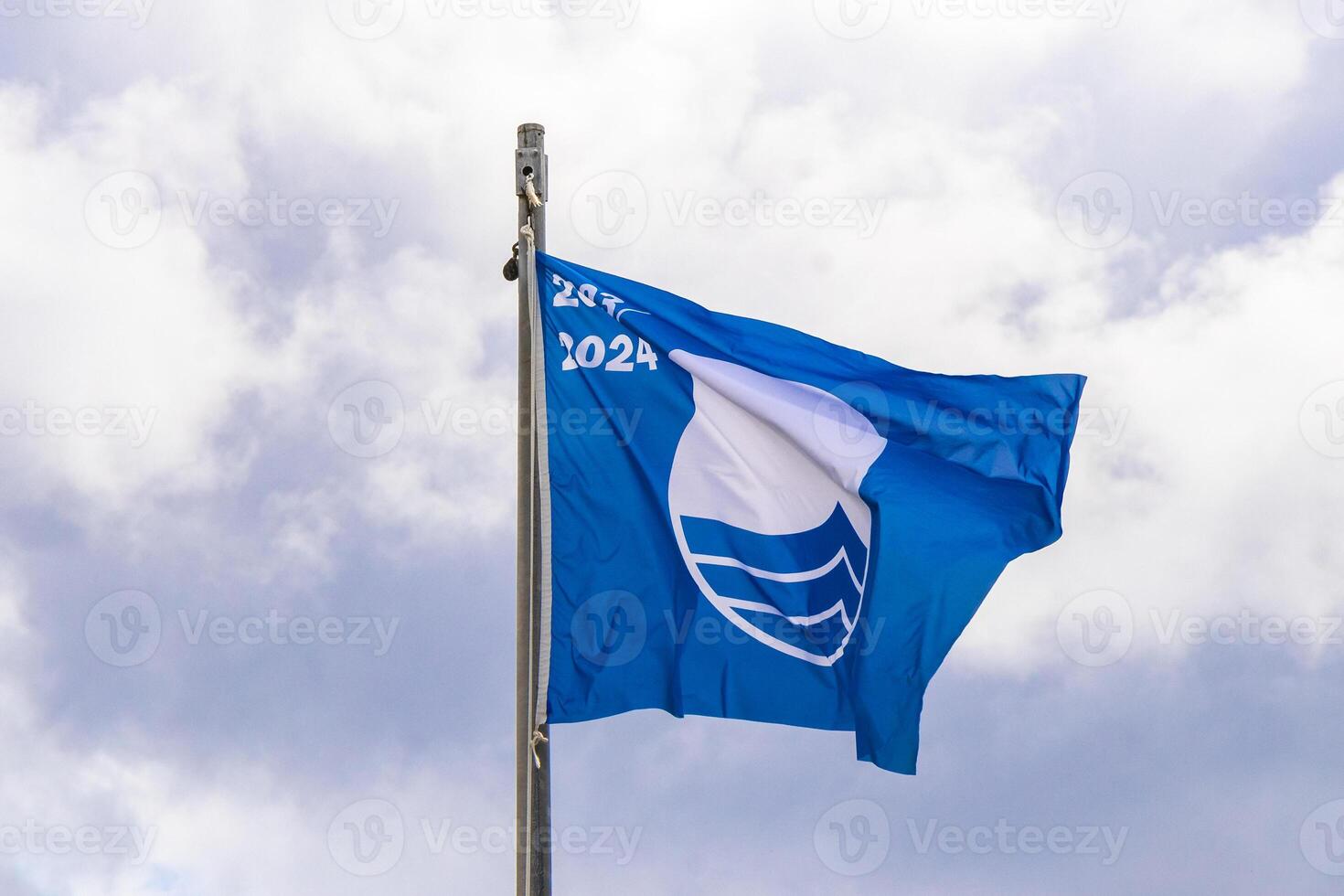 Blue flag with cloudy windy sky at certificated beach in Mexico. photo