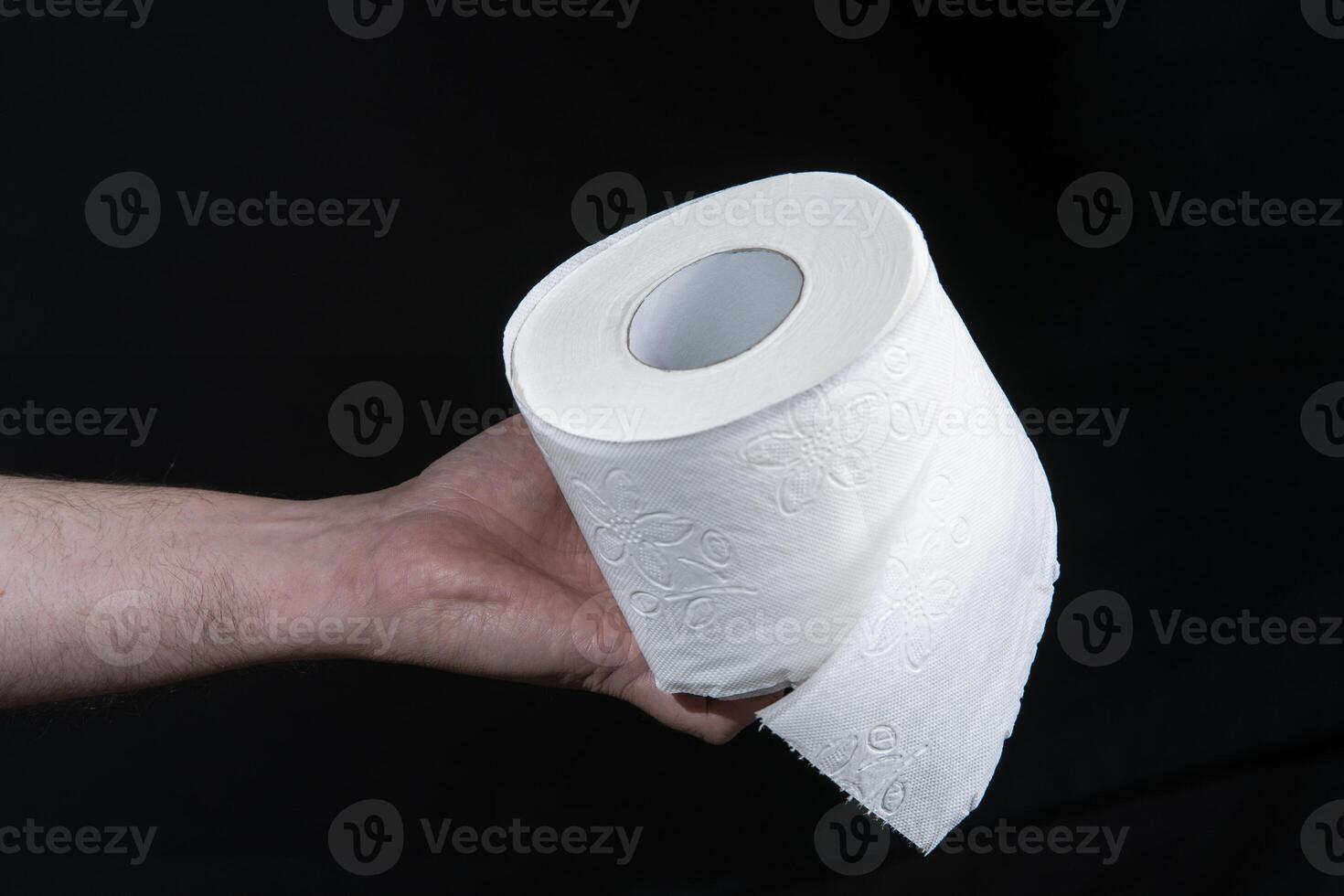 Close-up of a man's hand holding a roll of white toilet paper photo