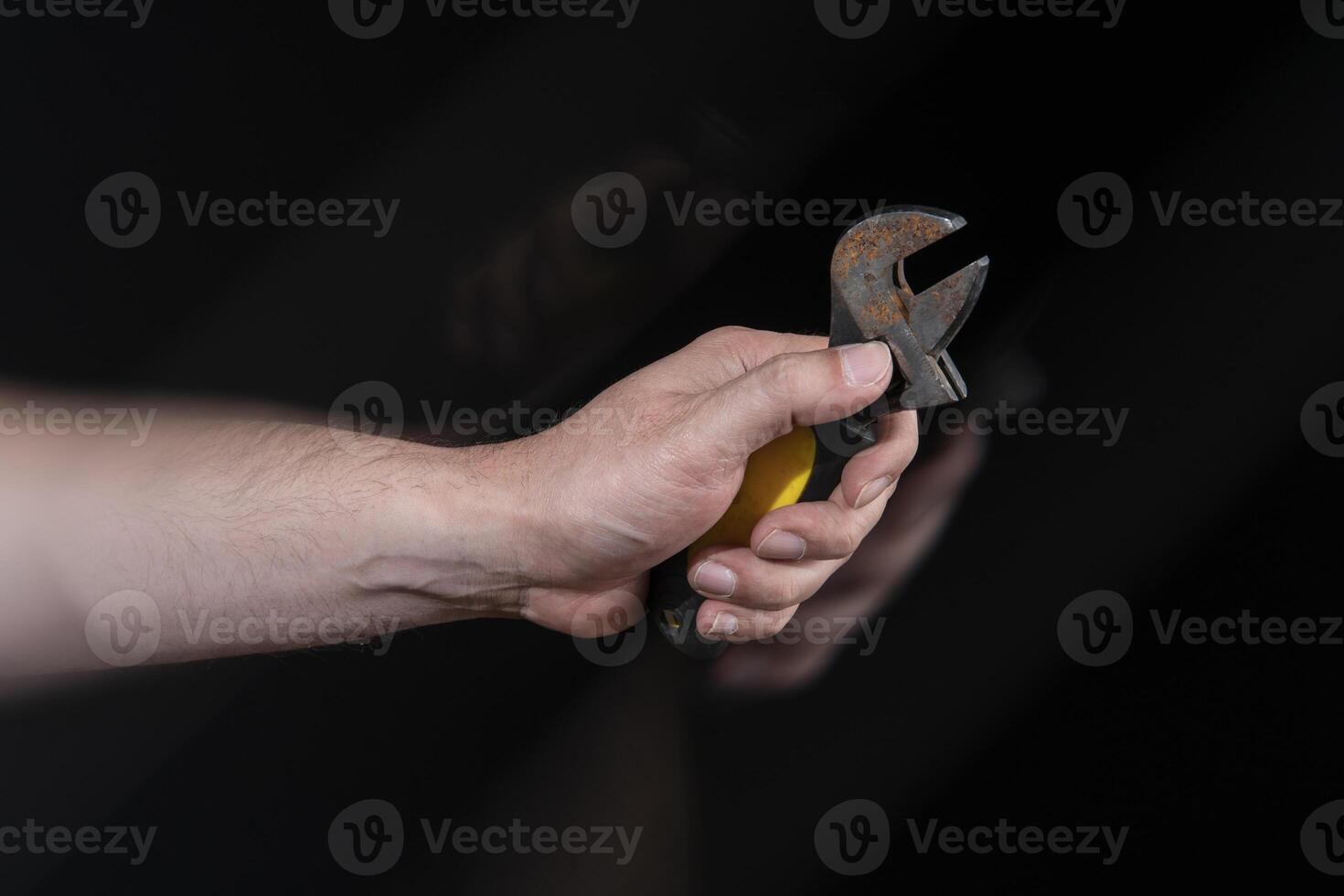 Close-up of man's hand holding a small mechanic's wrench with motion effect photo