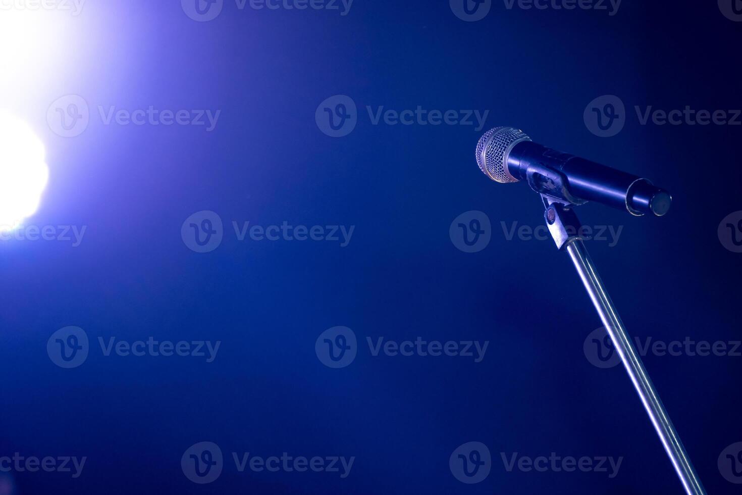Close-up the microphone on stand for speaker speech at seminar room with blue light background and blur bokeh, Presentation microphone on a stand, Copy space photo