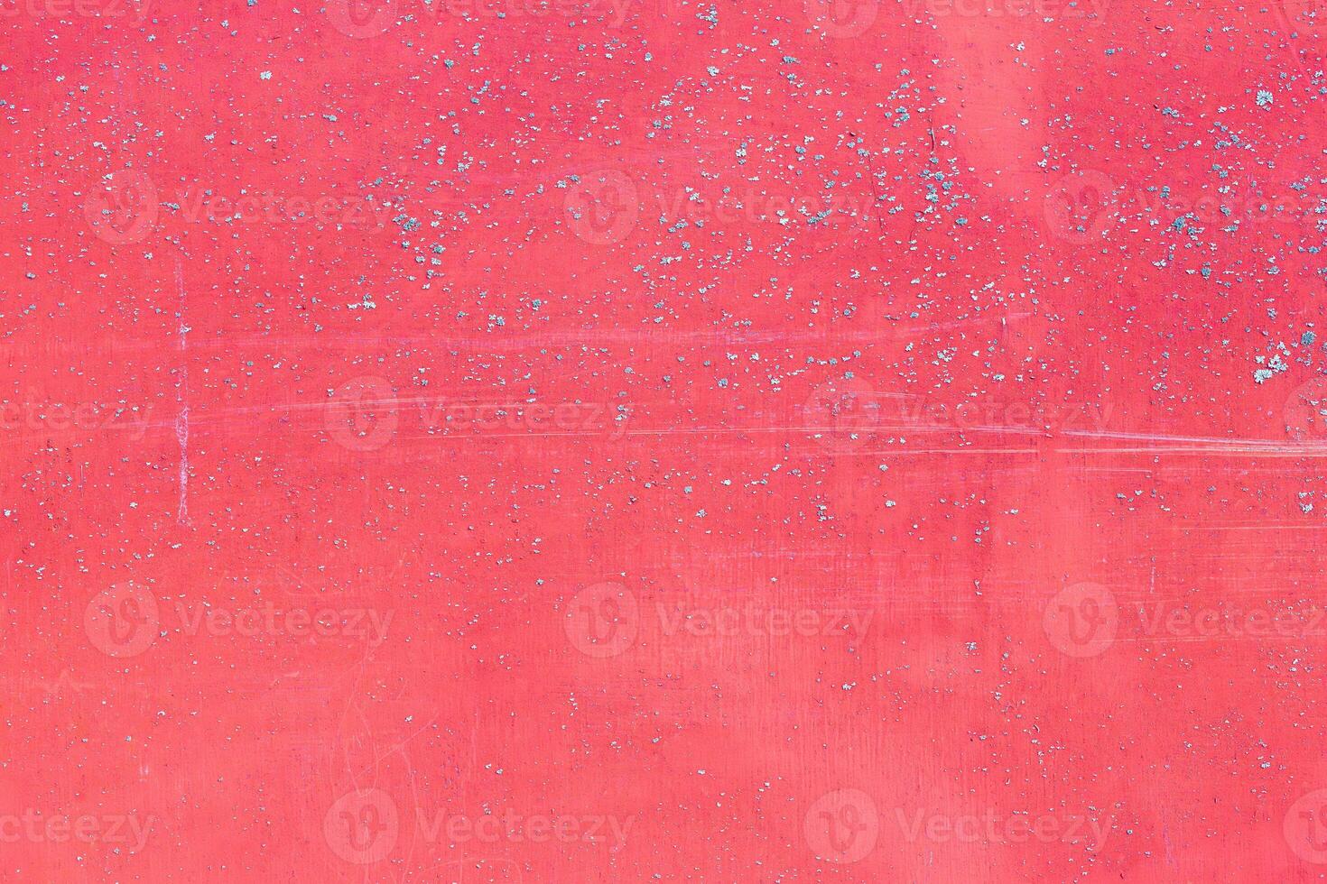 The texture of a pink surface with splashes of blue. A wall or other surface is scuffed and lightly scratched, painted a bright pink, with visible signs of wear and aging photo