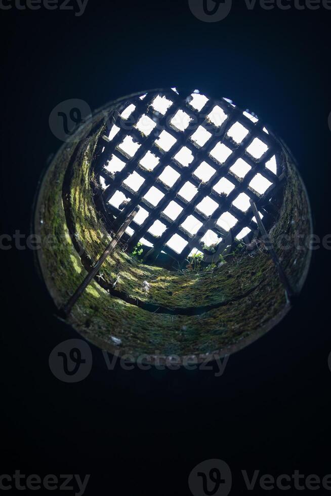 view from the dungeon upwards through a hatch covered with a grate photo