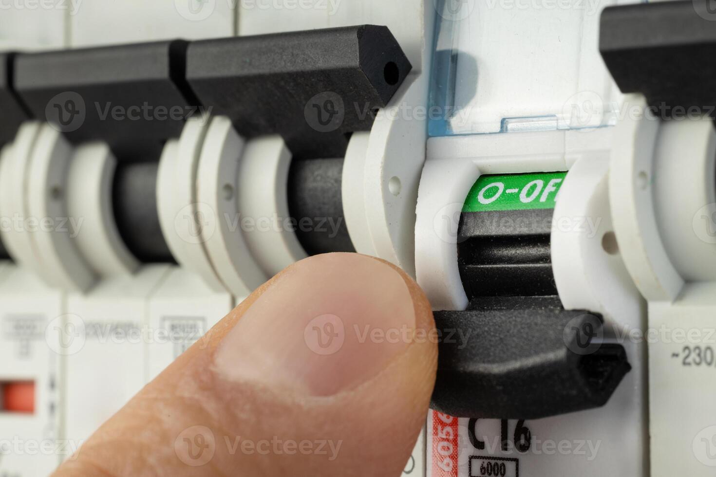 Hand flipping electrical switch in breaker panel photo