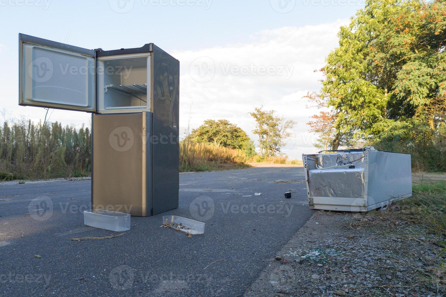 Discarded refrigerator and broken appliance on the roadside photo