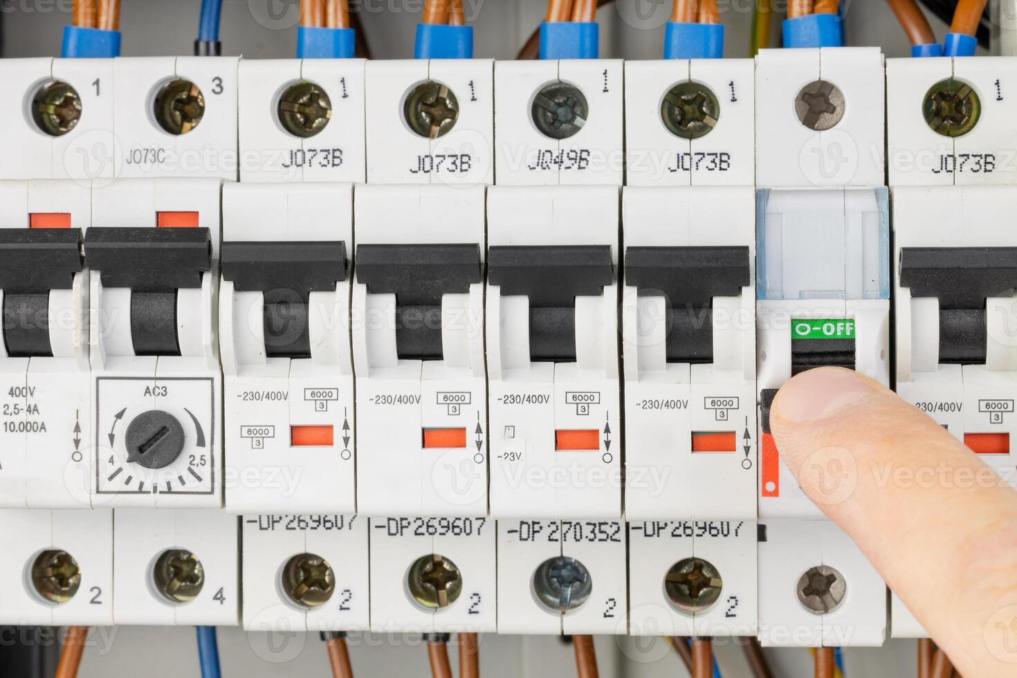 Finger pressing circuit breaker in electrical control panel photo