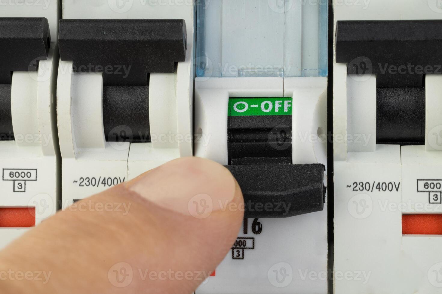Hand turning off electrical circuit breaker in control panel photo