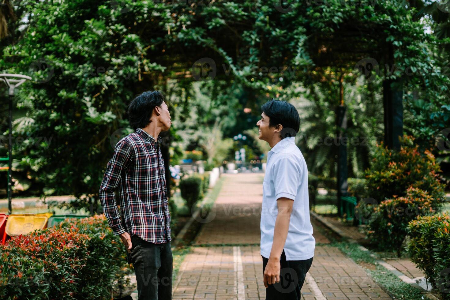 Two Southeast Asian men engaged in a lively conversation at a city square. photo