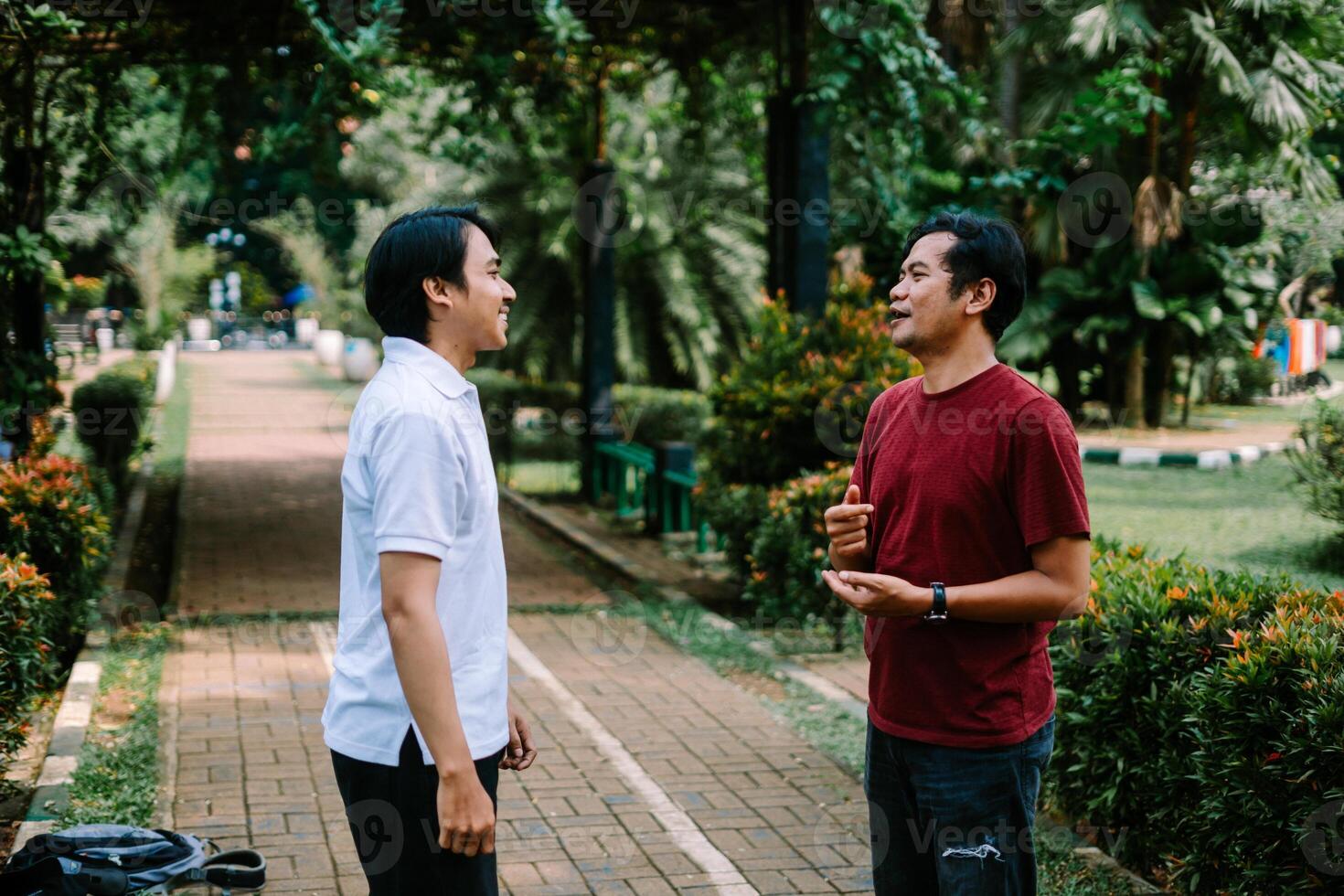 Two Southeast Asian men engaged in a lively conversation at a city square. photo