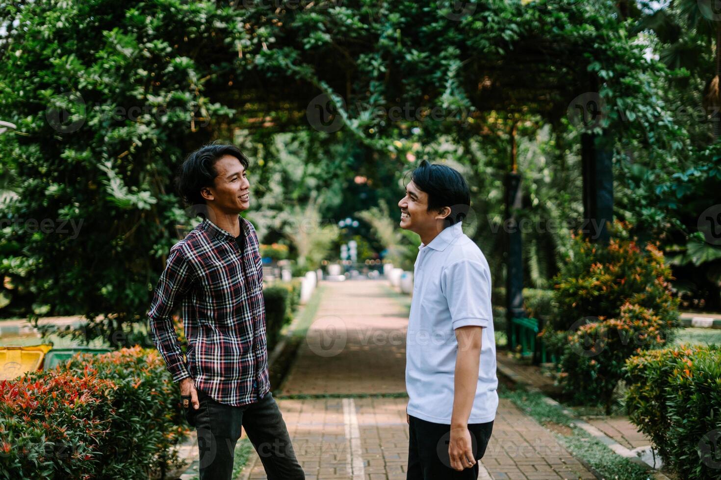 Two Southeast Asian men engaged in a lively conversation at a city square. photo