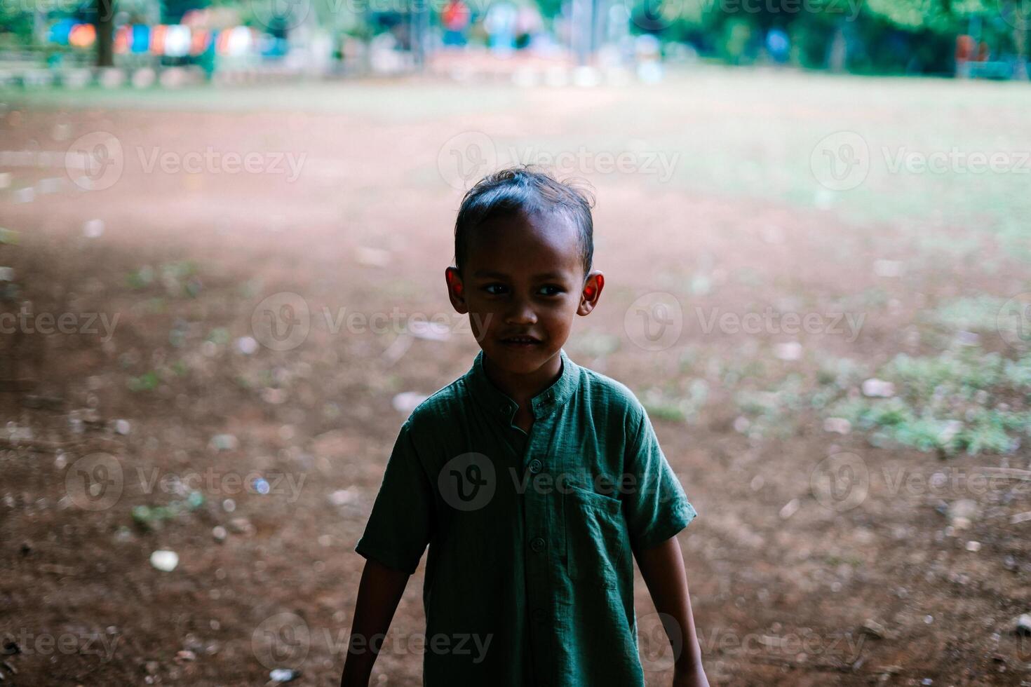 A young child standing in an open field, surrounded by greenery photo