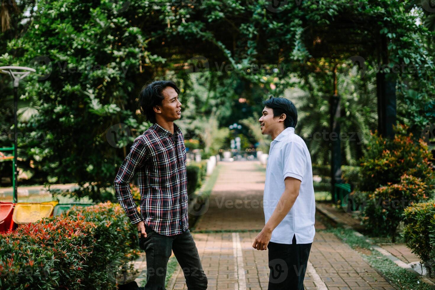 Two Southeast Asian men engaged in a lively conversation at a city square. photo