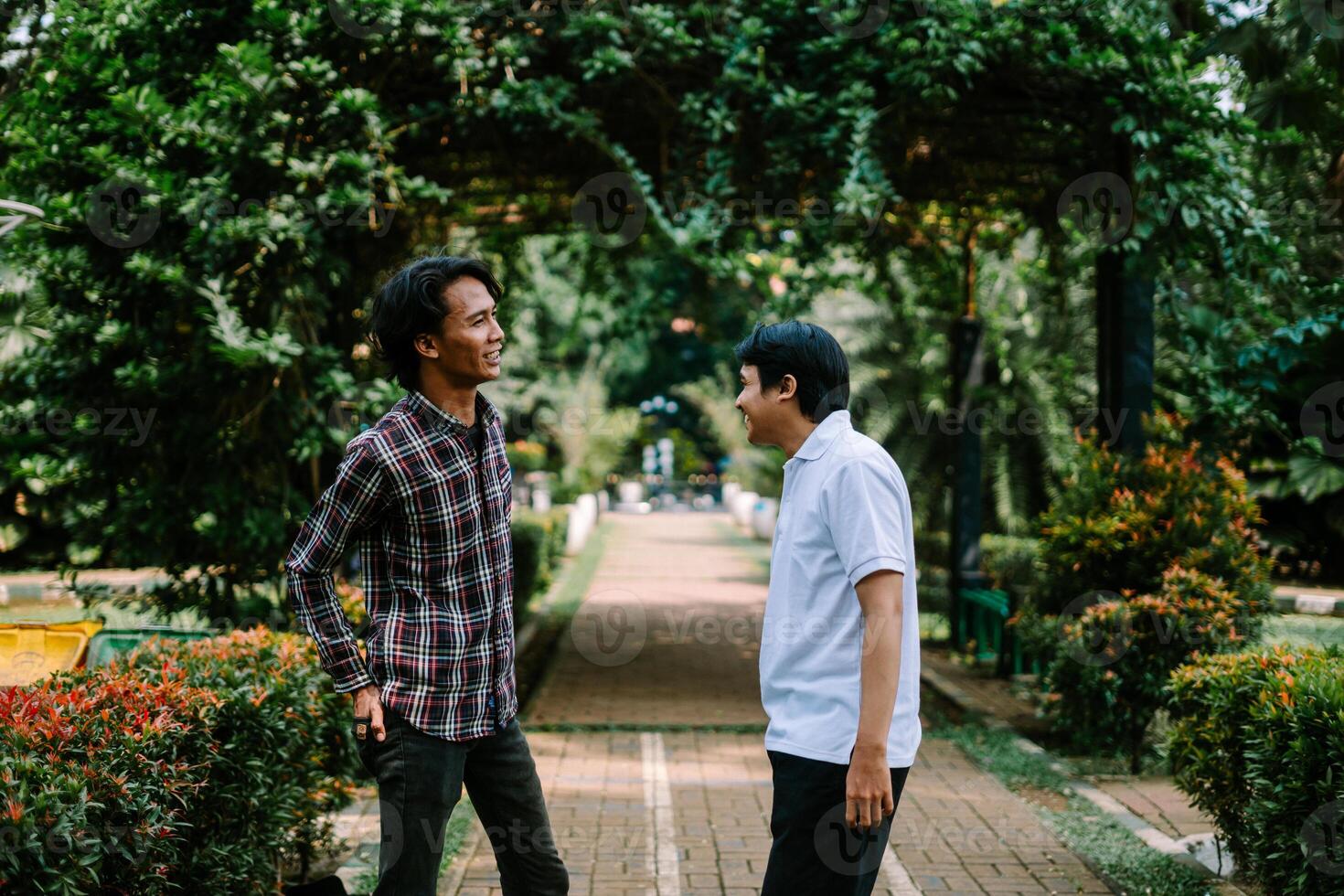 Two Southeast Asian men engaged in a lively conversation at a city square. photo