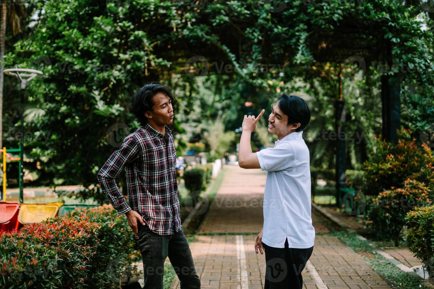 Two Southeast Asian men engaged in a lively conversation at a city square. photo
