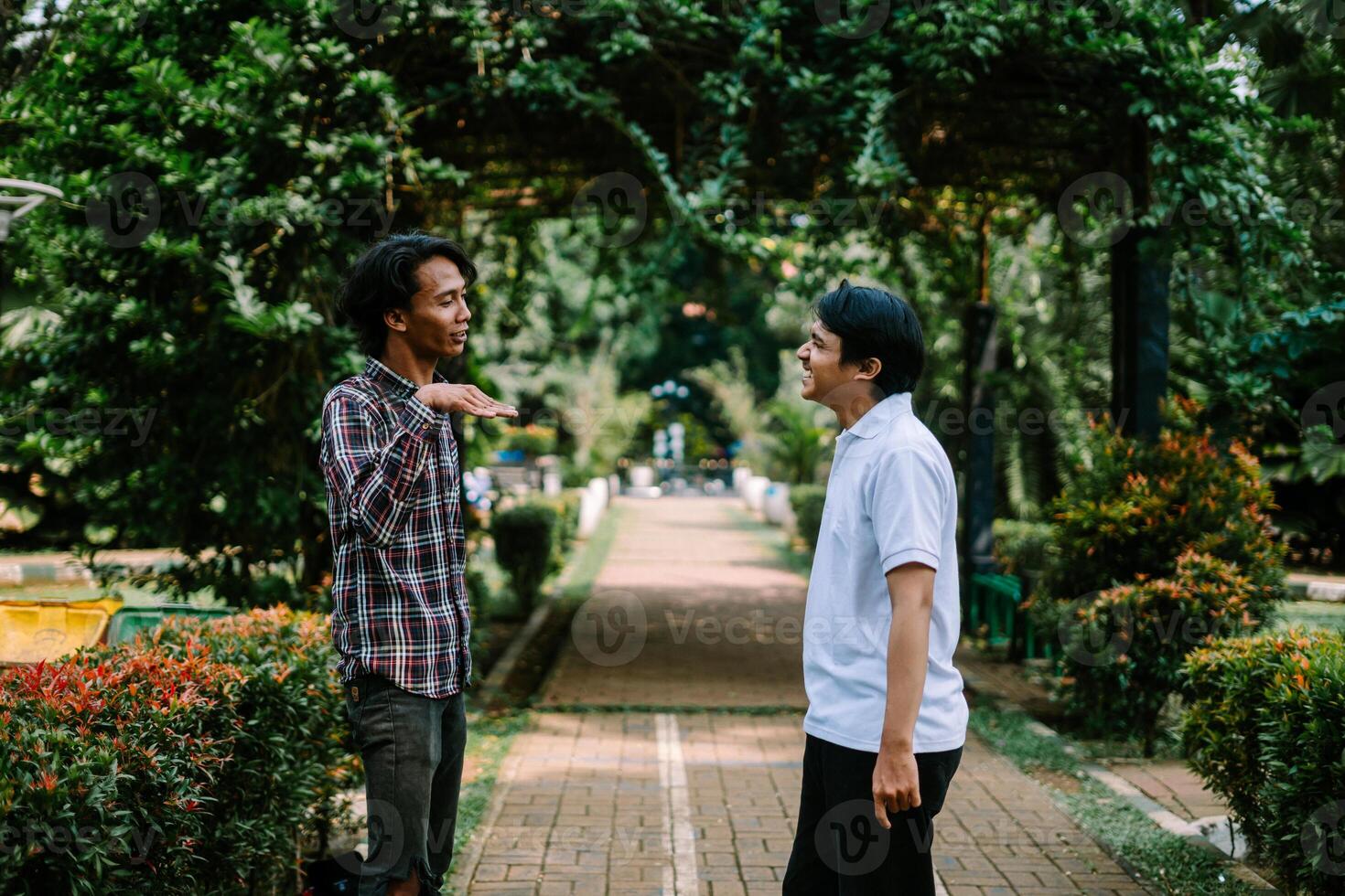 Two Southeast Asian men engaged in a lively conversation at a city square. photo