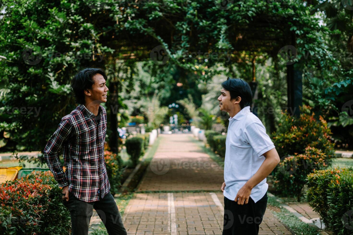 Two Southeast Asian men engaged in a lively conversation at a city square. photo