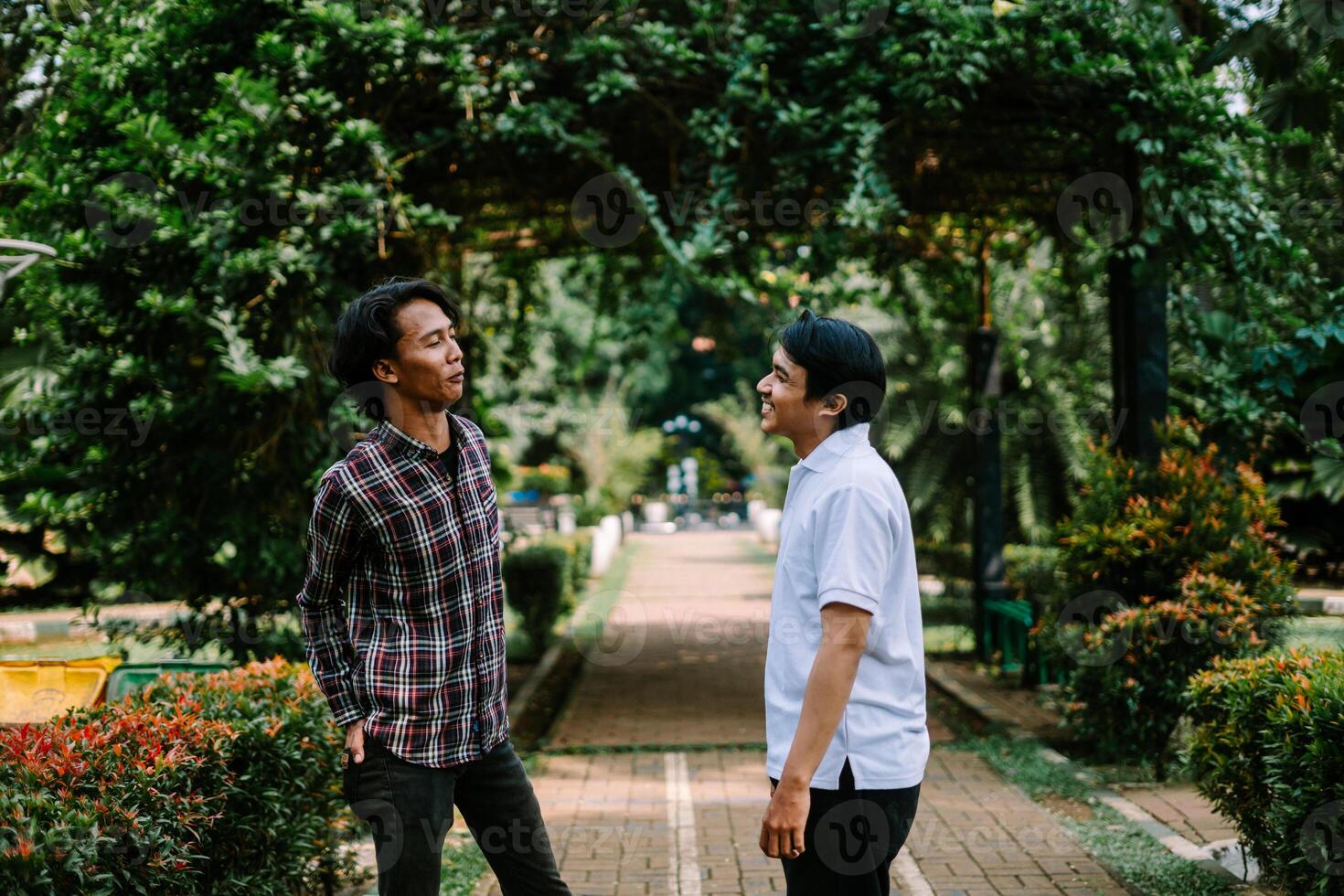 Two Southeast Asian men engaged in a lively conversation at a city square. photo