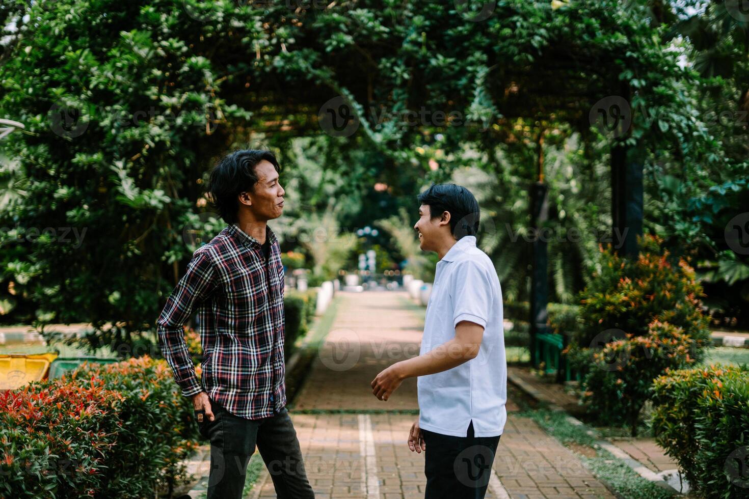 Two Southeast Asian men engaged in a lively conversation at a city square. photo