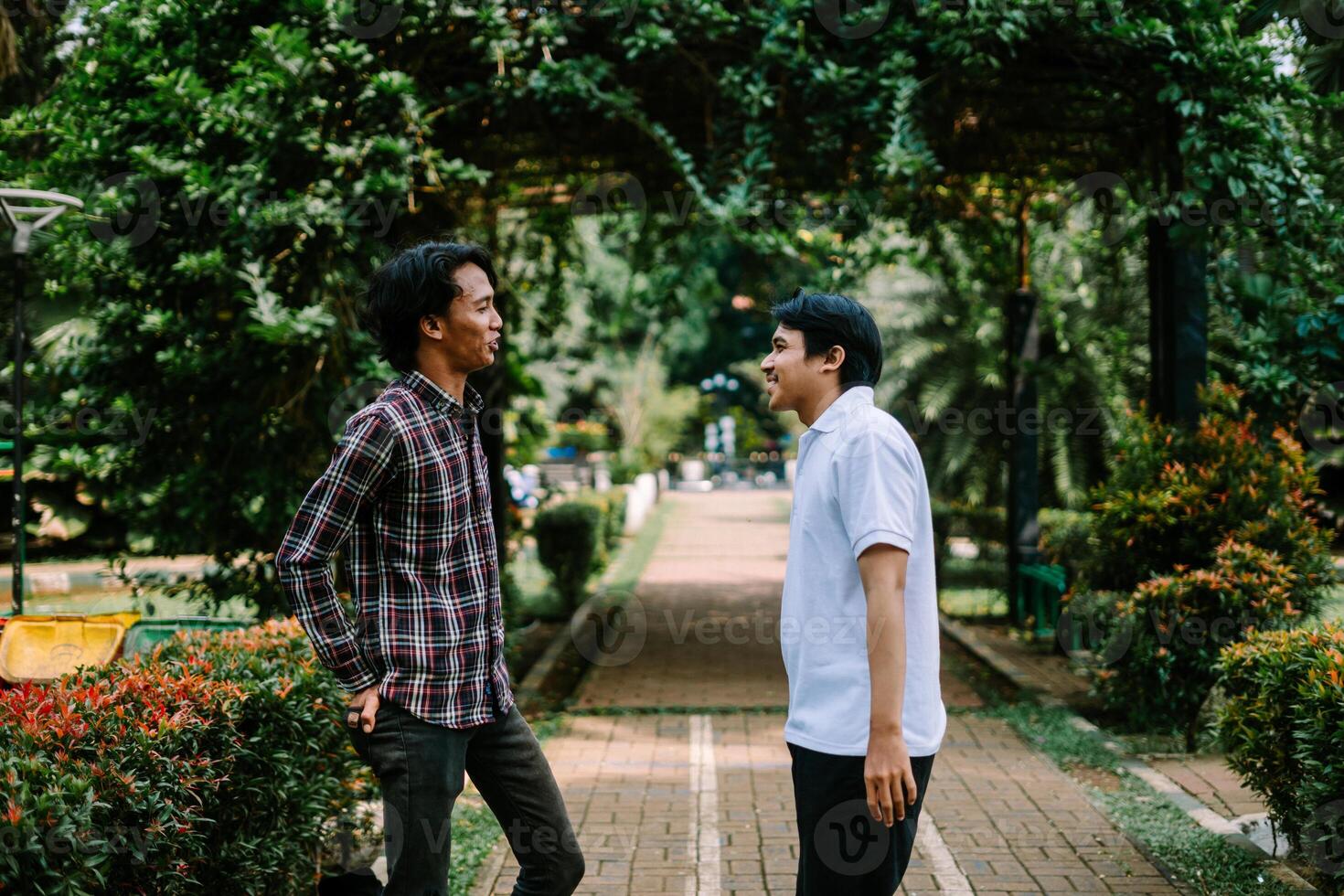 Two Southeast Asian men engaged in a lively conversation at a city square. photo