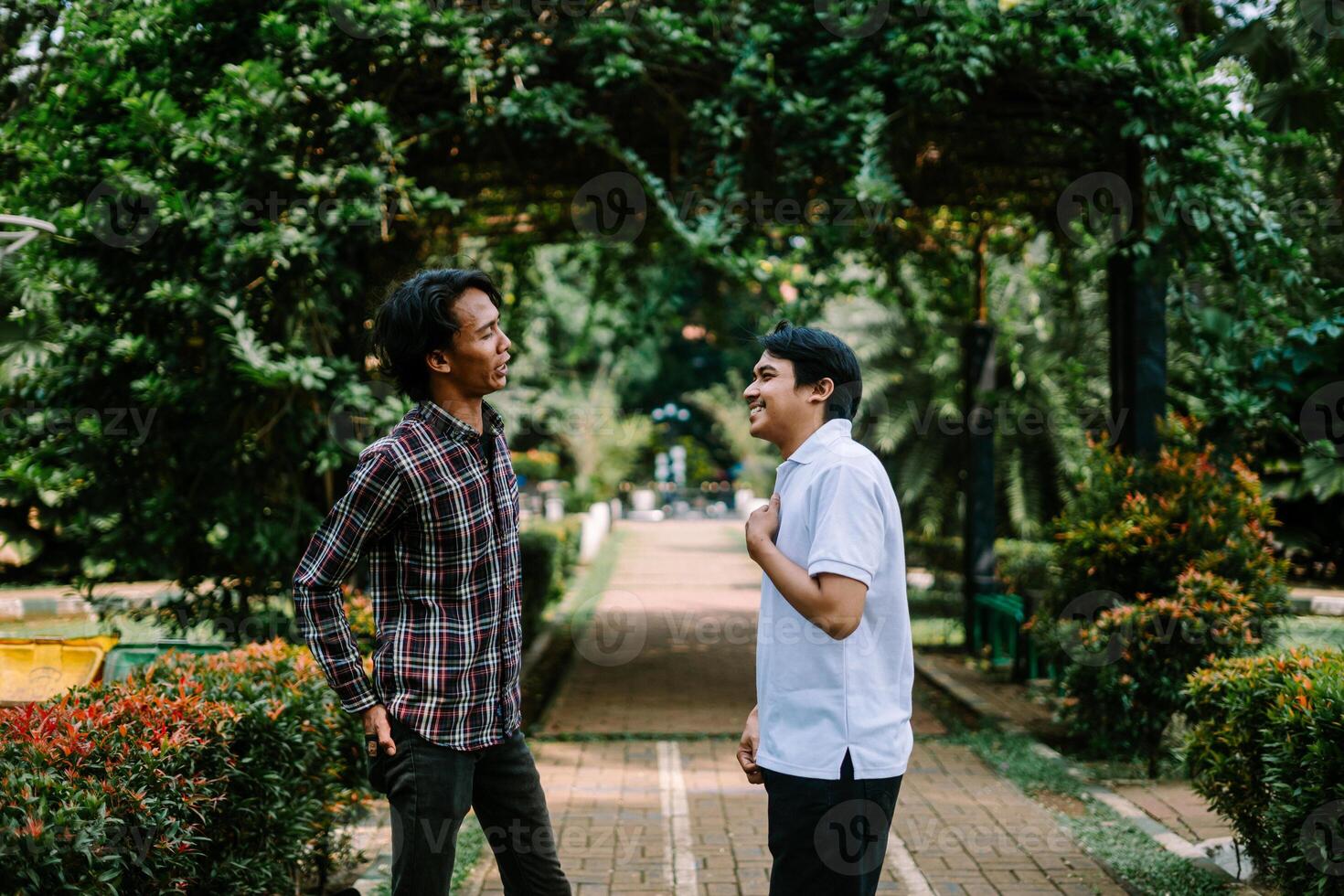 Two Southeast Asian men engaged in a lively conversation at a city square. photo