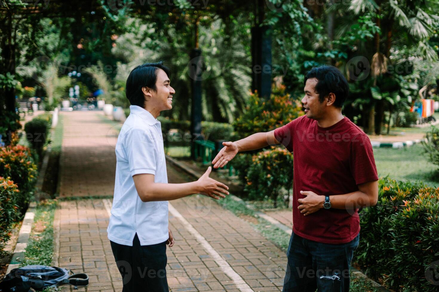 Two Southeast Asian men engaged in a lively conversation at a city square. photo