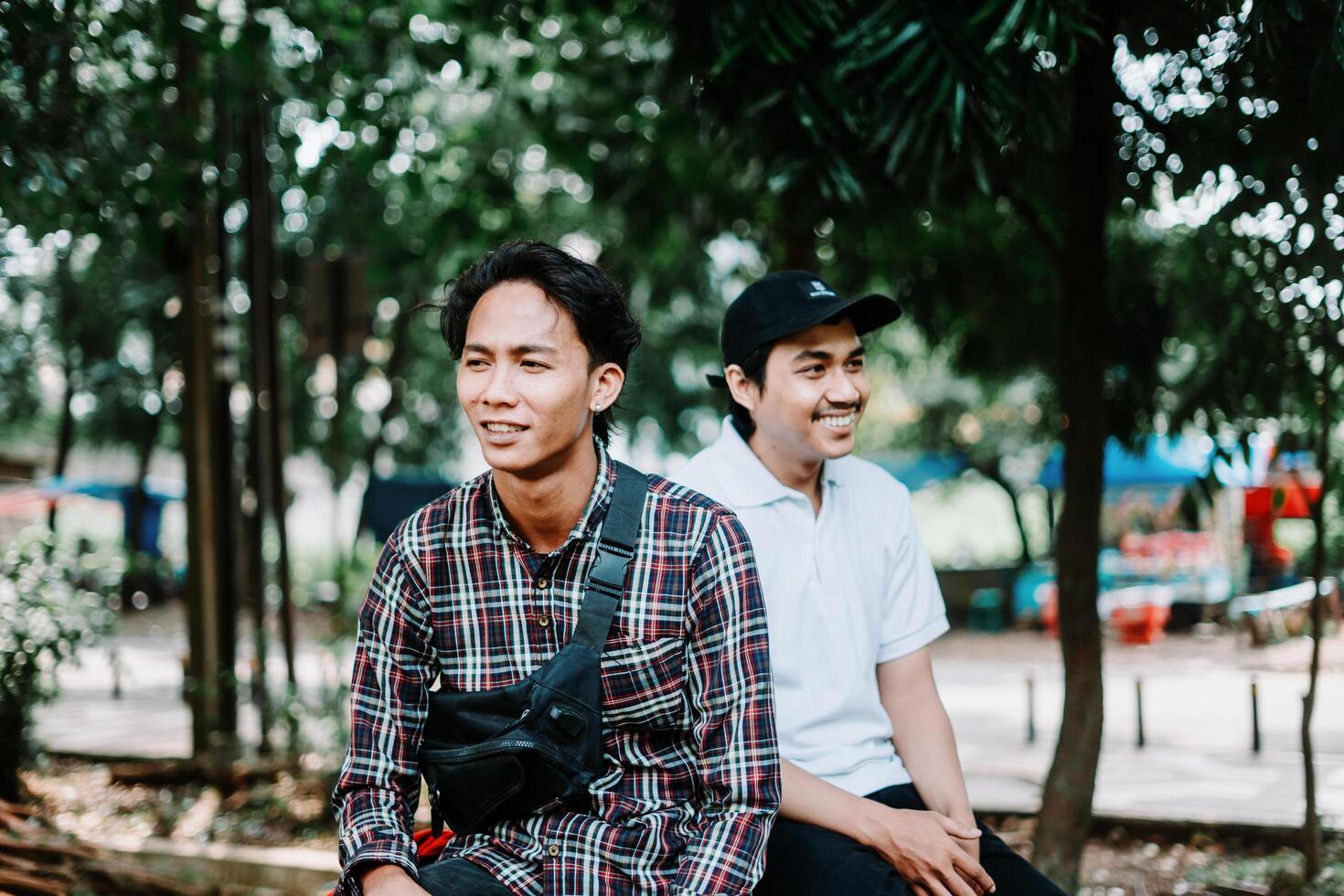 Two Southeast Asian men sitting in a city square, capturing a moment of relaxation and conversation photo