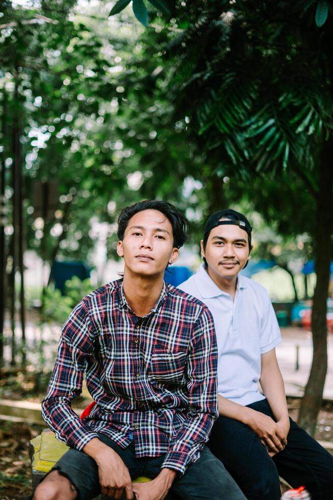 Two Southeast Asian men sitting in a city square, capturing a moment of relaxation and conversation photo