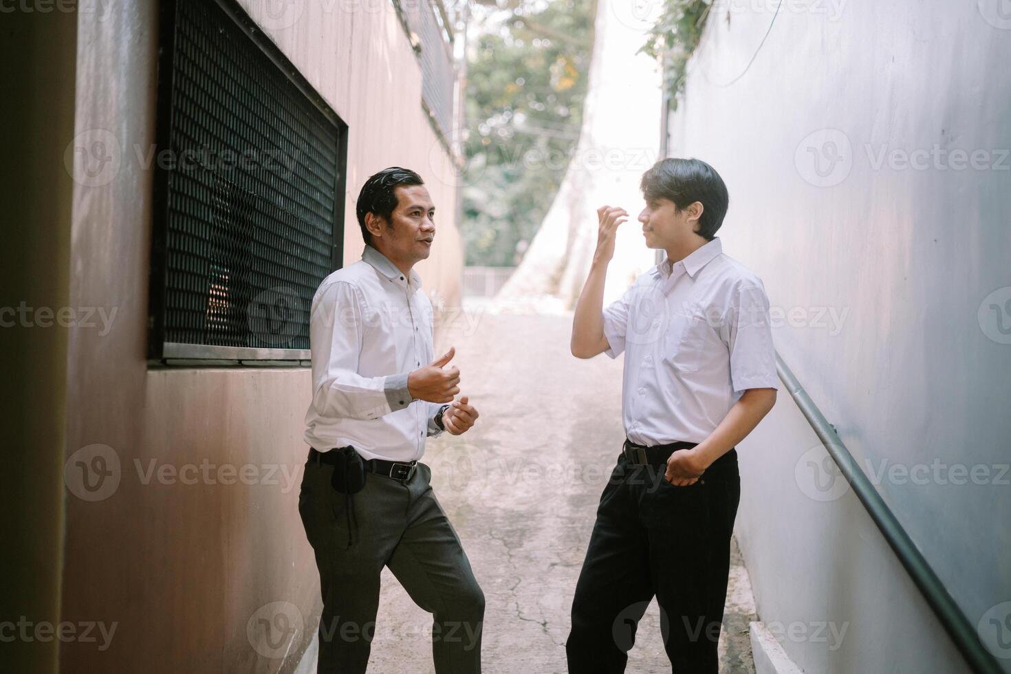 Two Southeast Asian businessmen engaged in a business discussion outdoors, standing in a professional setting photo