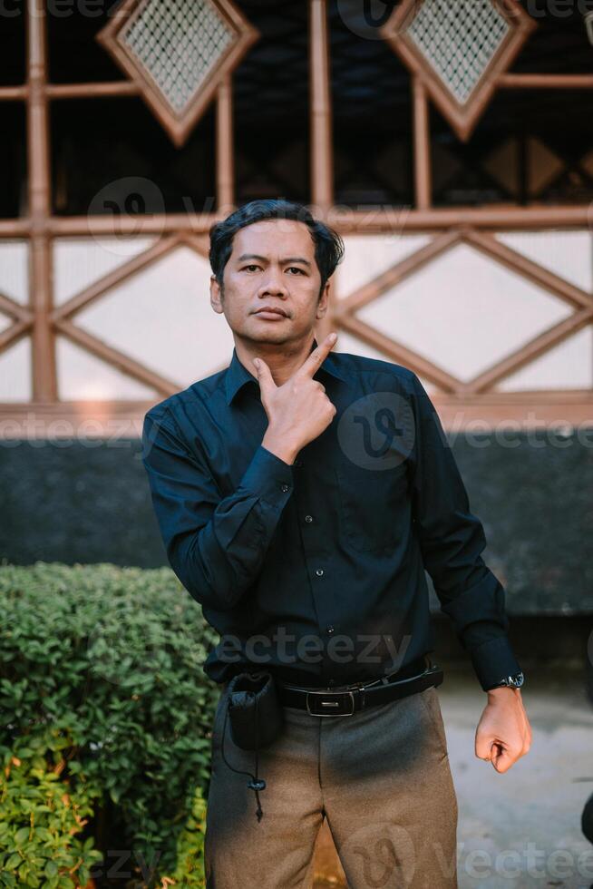 Southeast Asian man dressed sharply, confidently striking a pose photo