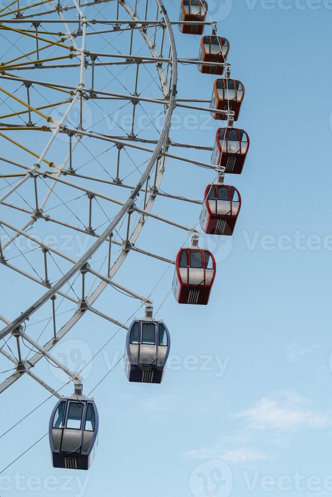 Part of the colorful Ferris wheel rises against the clear sky, inviting guests to the amusement park. photo