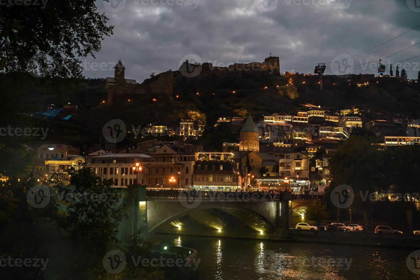Enchanting evening lights illuminate historic architecture along the river in Tbilisi, Georgia photo