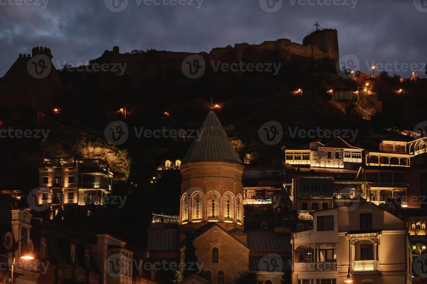 A serene evening in Tbilisi, an illuminated old church against a dramatic skyline photo