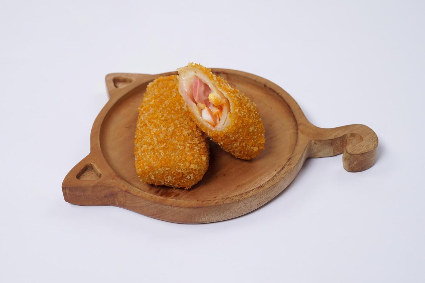 American Risoles or risoles mayo is a traditional Indonesian snack filled with smoked beef or sausage, boiled eggs and mayonnaise. Crispy texture on the outside. Risoles on wood plate isolated white. photo