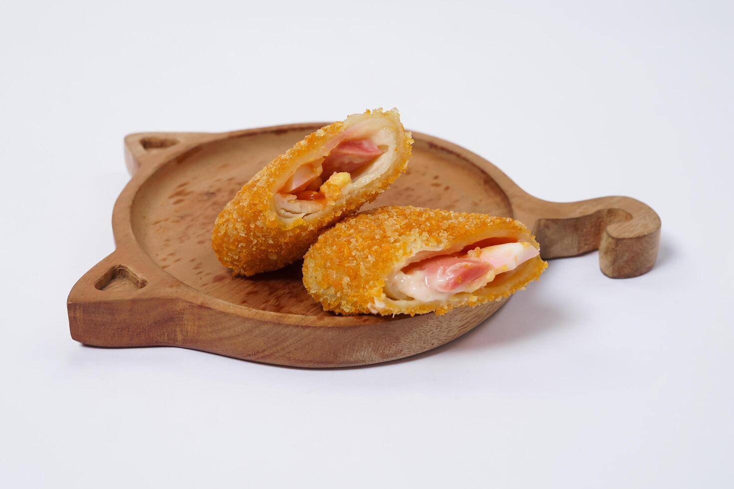 American Risoles or risoles mayo is a traditional Indonesian snack filled with smoked beef or sausage, boiled eggs and mayonnaise. Crispy texture on the outside. Risoles on wood plate isolated white. photo