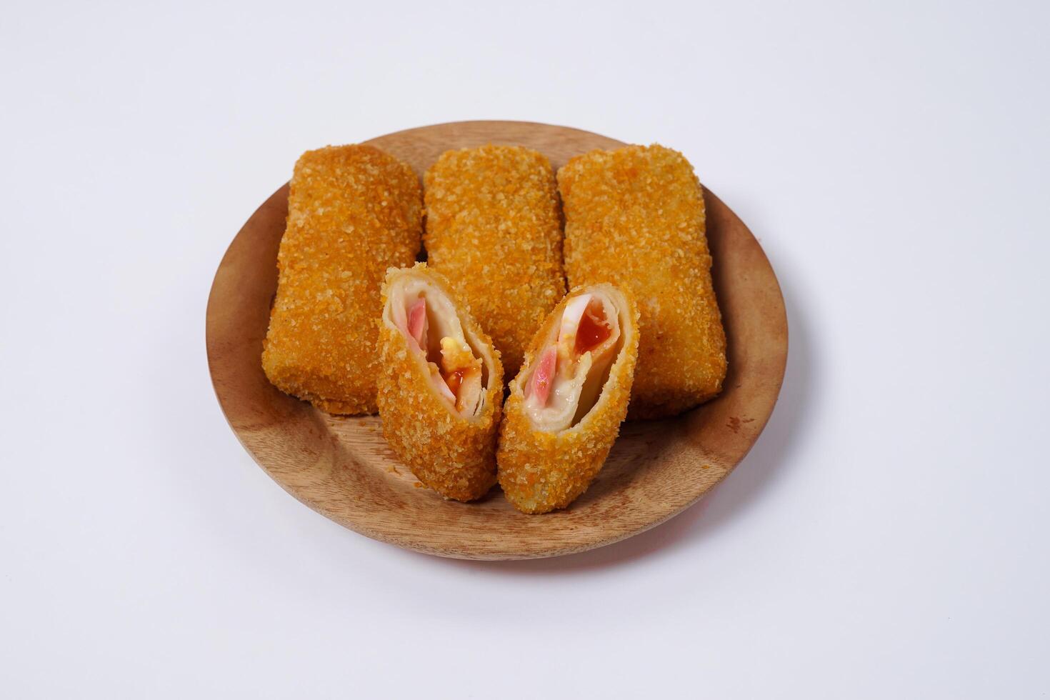 American Risoles or risoles mayo is a traditional Indonesian snack filled with smoked beef or sausage, boiled eggs and mayonnaise. Crispy texture on the outside. Risoles on wood plate isolated white. photo