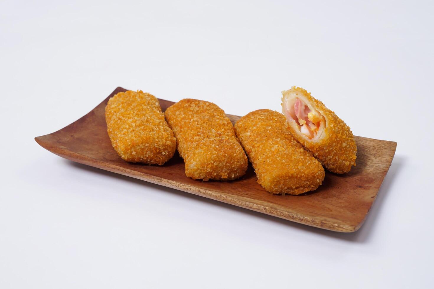 American Risoles or risoles mayo is a traditional Indonesian snack filled with smoked beef or sausage, boiled eggs and mayonnaise. Crispy texture on the outside. Risoles on wood plate isolated white. photo