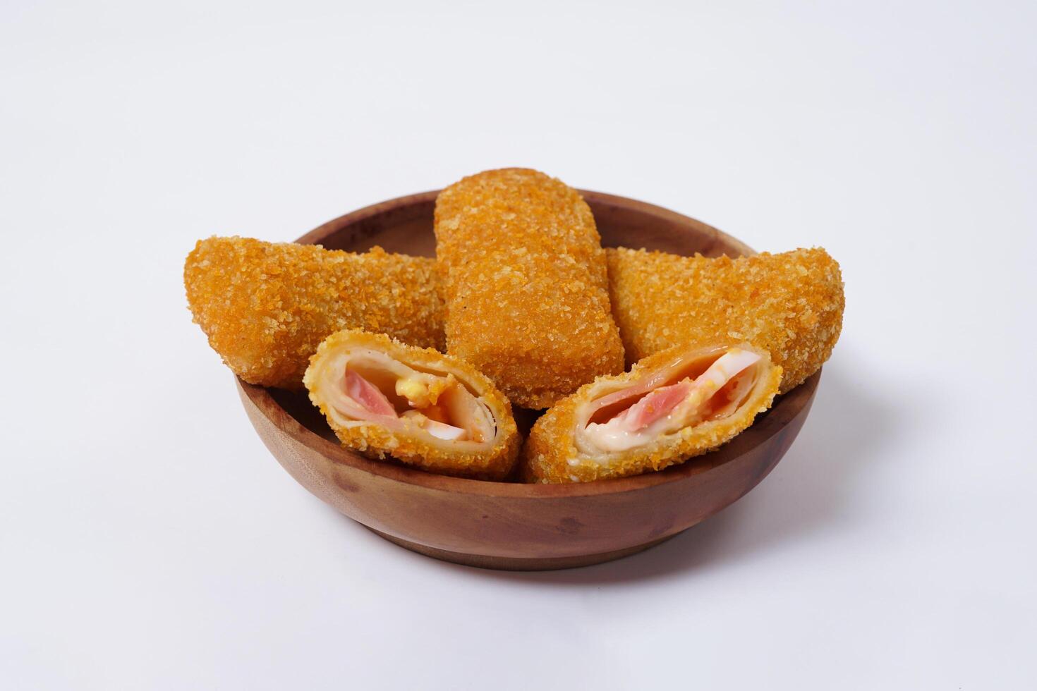 American Risoles or risoles mayo is a traditional Indonesian snack filled with smoked beef or sausage, boiled eggs and mayonnaise. Crispy texture on the outside. Risoles on wood plate isolated white. photo