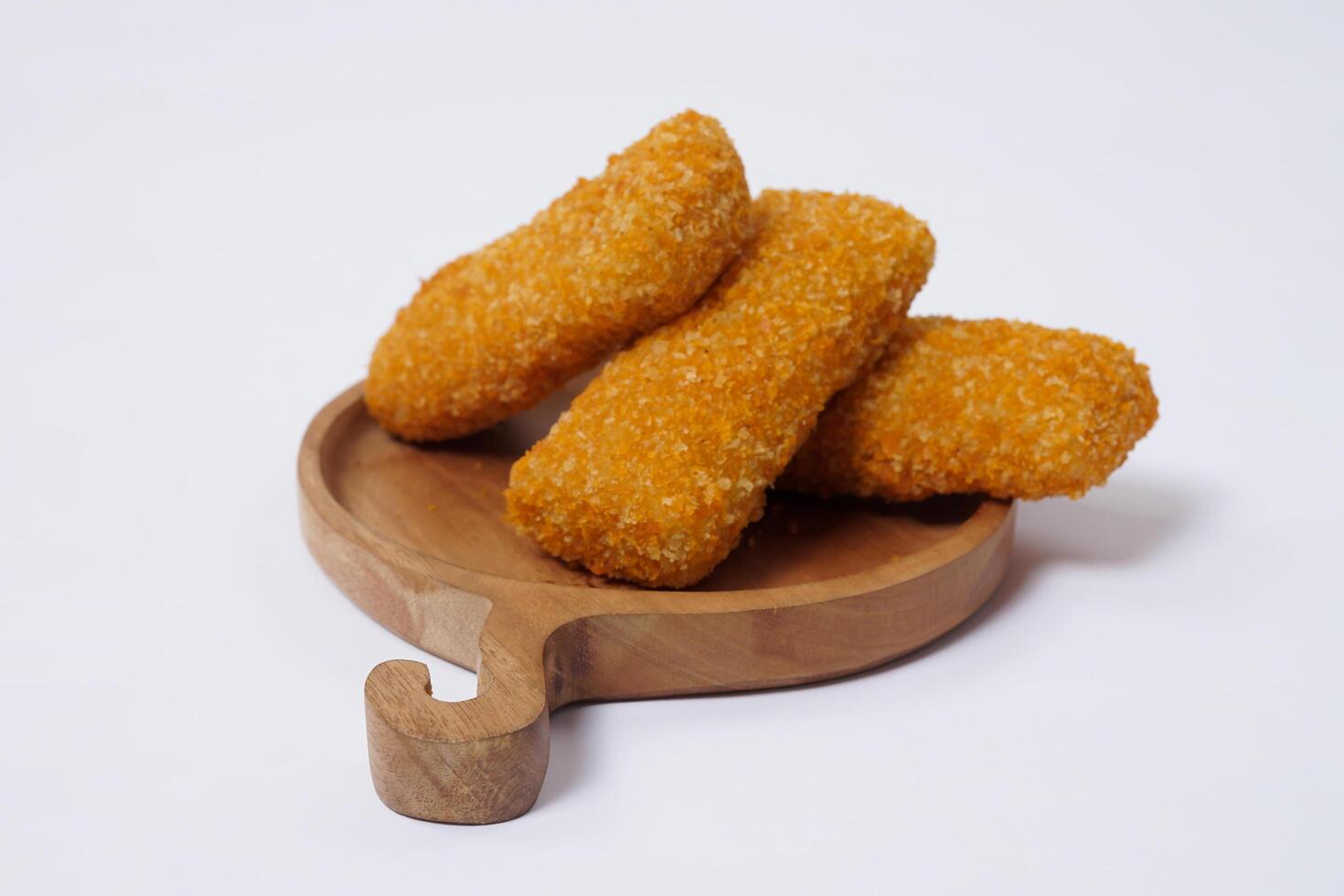 American Risoles or risoles mayo is a traditional Indonesian snack filled with smoked beef or sausage, boiled eggs and mayonnaise. Crispy texture on the outside. Risoles on wood plate isolated white. photo