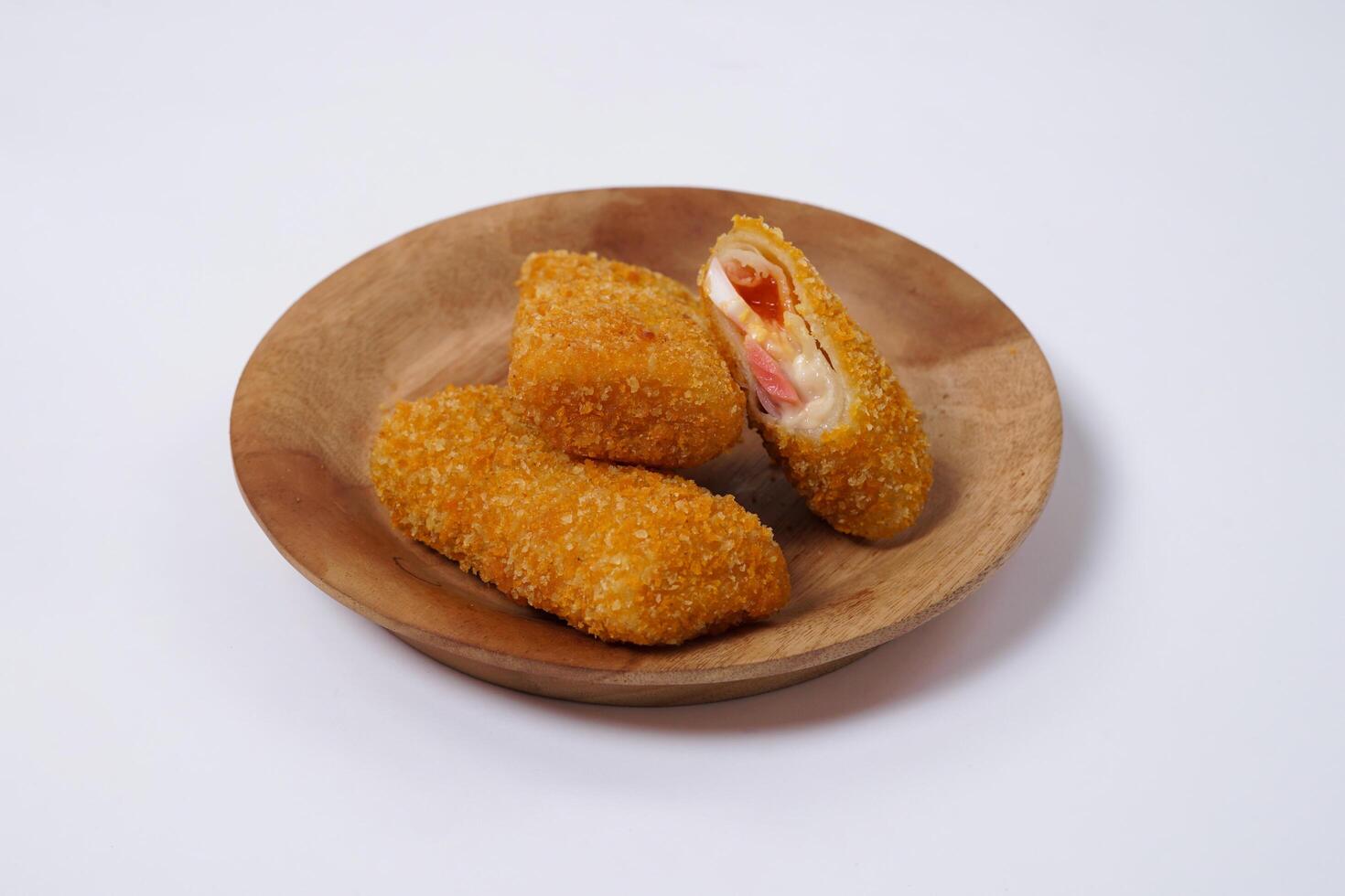 American Risoles or risoles mayo is a traditional Indonesian snack filled with smoked beef or sausage, boiled eggs and mayonnaise. Crispy texture on the outside. Risoles on wood plate isolated white. photo