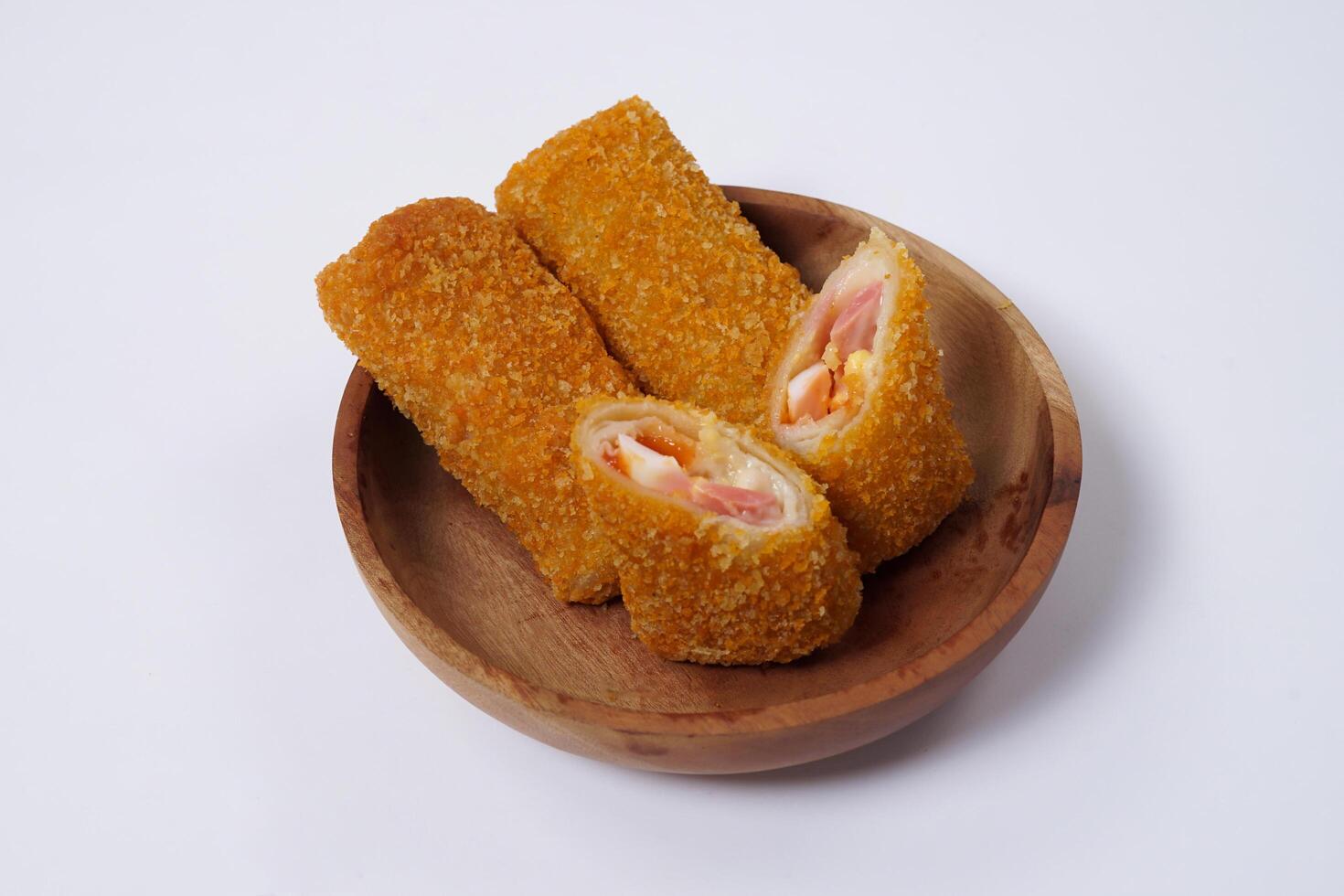 American Risoles or risoles mayo is a traditional Indonesian snack filled with smoked beef or sausage, boiled eggs and mayonnaise. Crispy texture on the outside. Risoles on wood plate isolated white. photo