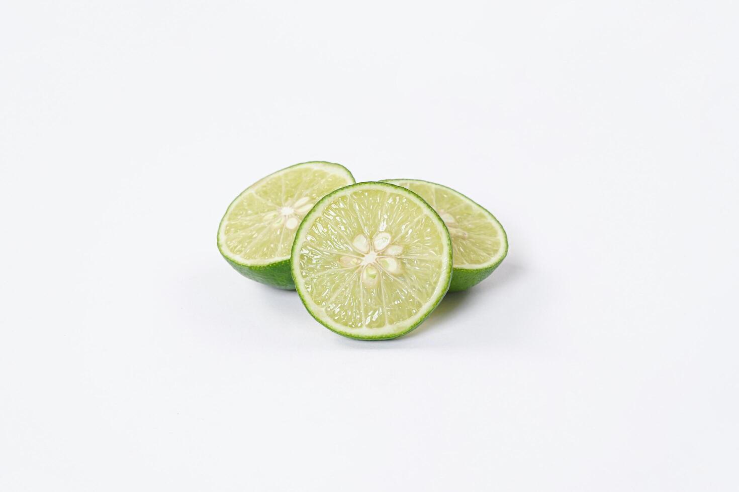 Lime fruit. Fresh, tangy lime with bright green skin and juicy interior. Ideal for culinary, healthy, and citrus-themed visuals. Ripe lime fruits with slices isolated on a white background. photo