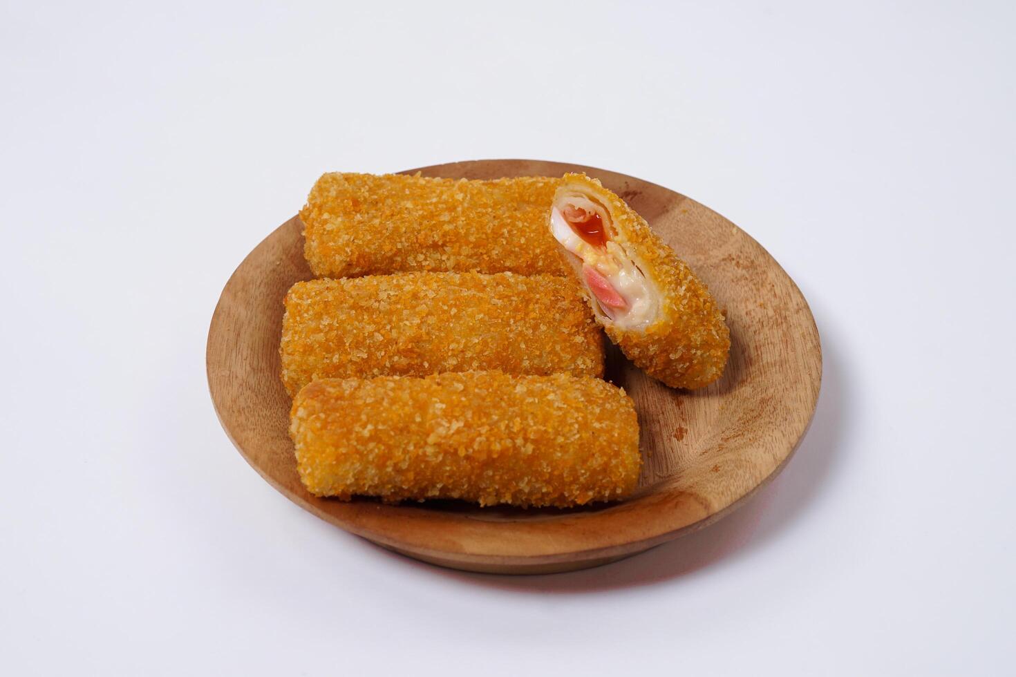 American Risoles or risoles mayo is a traditional Indonesian snack filled with smoked beef or sausage, boiled eggs and mayonnaise. Crispy texture on the outside. Risoles on wood plate isolated white. photo